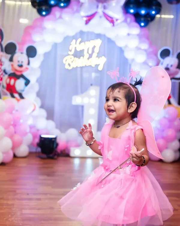 A delightful shot of the birthday girl in her pink fairy costume, smiling with excitement amidst the party decorations.