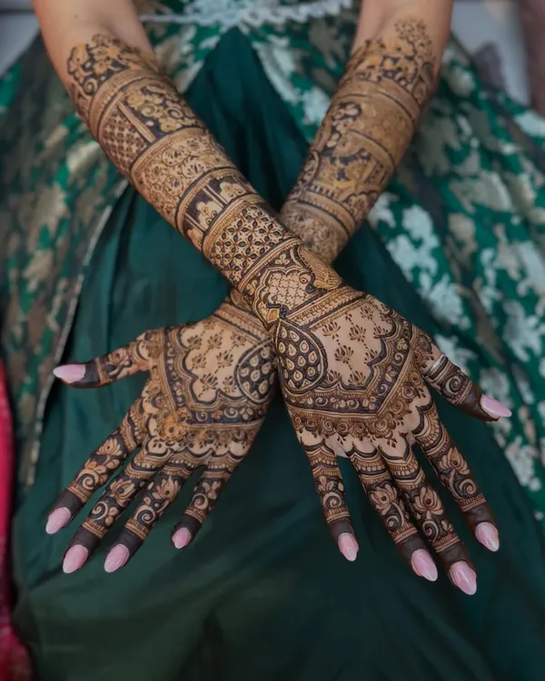 A stunning full-sleeve bridal mehendi that combines geometric patterns with traditional figures. This design is for the bride who wants to make a grand statement.