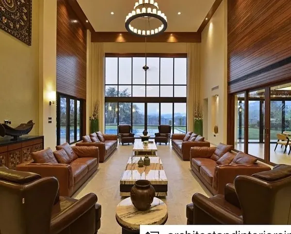 This double-height living room in a Khandala weekend home was designed to be a grand yet intimate space for family gatherings. The large windows frame the picturesque valley views, seamlessly blending the indoors with the outdoors and creating an atmosphere of expansive tranquility.