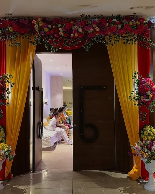 An impressive entrance I created for a banquet hall, using red and yellow drapes with large floral bouquets. It frames the doorway beautifully and sets a grand tone for the event inside.