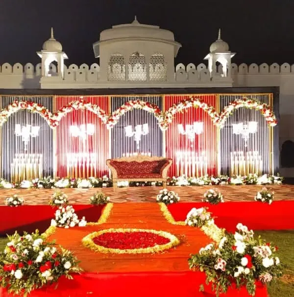 A magnificent wedding stage set against a heritage property, blending royal architecture with classic red and white decor for a timeless look.