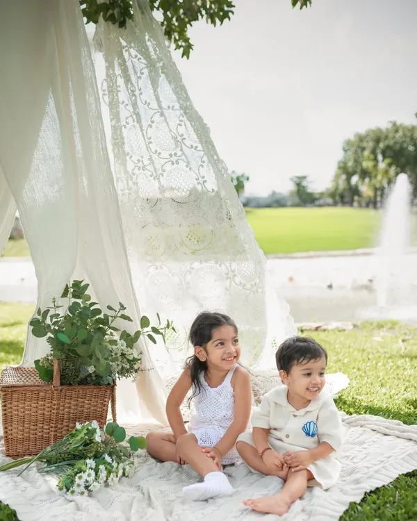 A sweet moment between siblings during an outdoor picnic photoshoot. I set up this lace tent and wicker basket to create a dreamy, boho atmosphere right in the park.