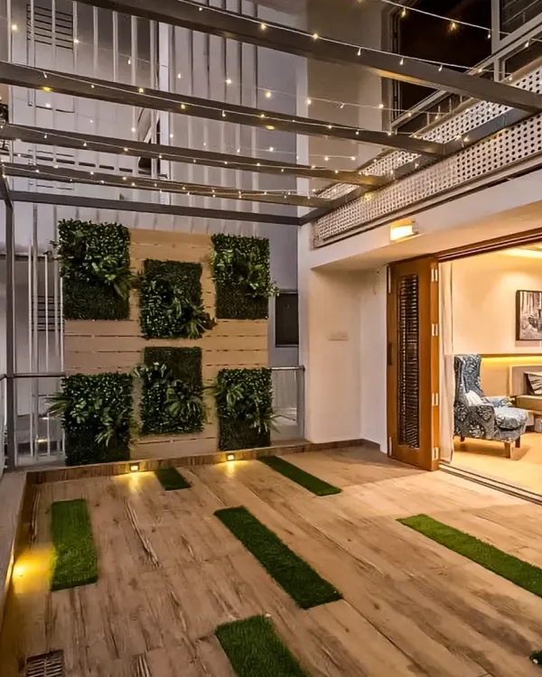 A spacious patio area that seamlessly connects with the indoors. We used a vertical garden, wood-like floor tiles with grass inserts, and charming string lights to create a perfect space for evening relaxation.