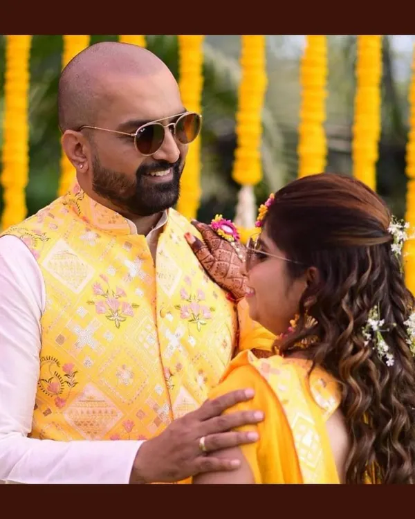 A happy couple during their Haldi ceremony. The groom's custom yellow waistcoat with floral embroidery is perfectly in sync with the bride's yellow saree, creating a bright and joyful look.