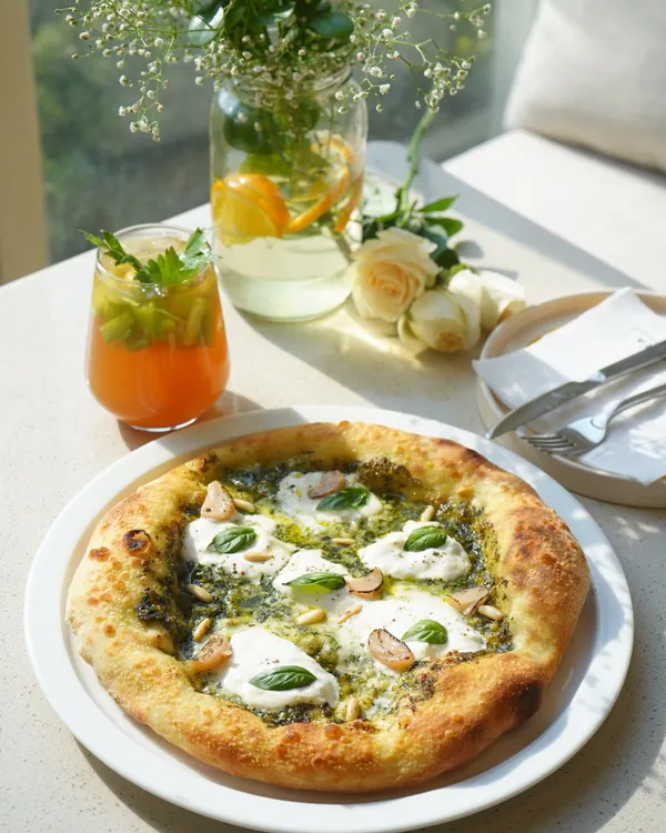 Our signature basil pesto pizza, featuring a generous spread of our farm-fresh pesto, dollops of creamy burrata, and roasted garlic. The Napoletana-style crust is perfectly charred and airy.
