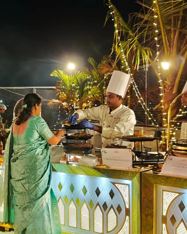 (Hero Item) Here is one of our chefs serving a guest at a beautiful outdoor wedding reception. We focus on flawless service and creating a warm, welcoming atmosphere, ensuring every guest feels pampered under the festive lights.