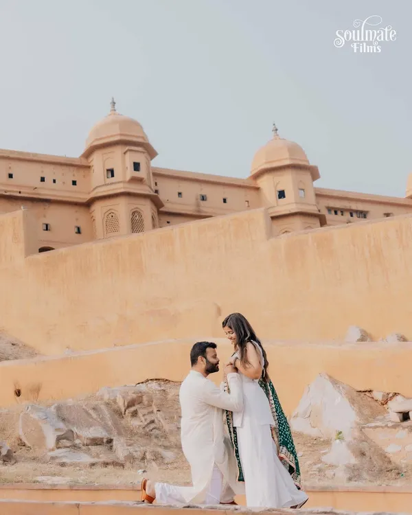 A regal pre-wedding portrait at Amer Fort in Jaipur. The groom-to-be gets on one knee, creating a timeless and romantic photograph against the backdrop of historic architecture.