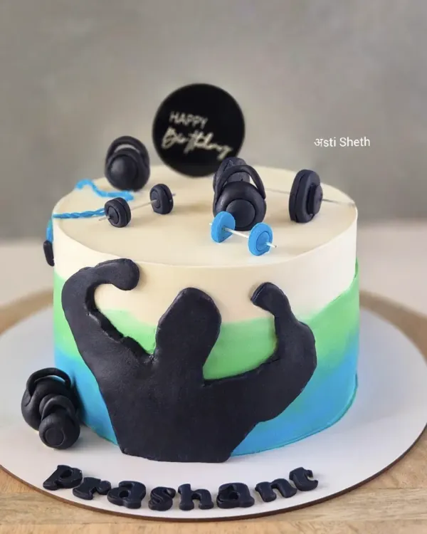 A cake for a fitness enthusiast, featuring a weightlifter silhouette and fondant dumbbells. The blue and green watercolour effect adds a modern touch.