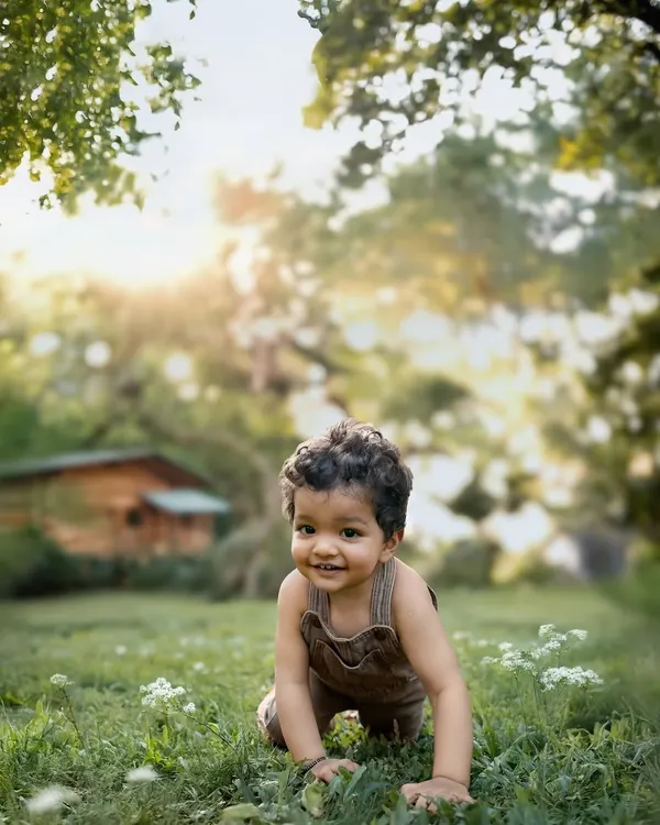 A toddler exploring a sunlit garden, crawling on the grass with a joyful smile. This is the magic of letting children be little, capturing their pure curiosity in the warm glow of natural light.