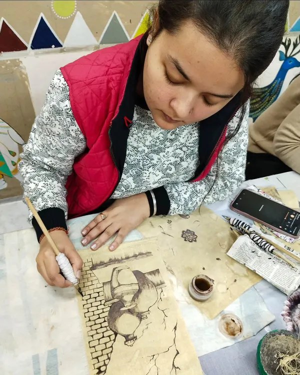 A student practicing the fine lines of Kalamkari painting, a traditional art form that involves freehand drawing and natural dyes.