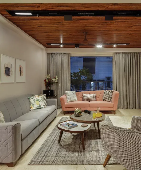 The living room at Rue 32 exudes comfort and style. We created an inviting enclave with a linear grey sofa, a rose pink loveseat, and a lounge chair in checks. The wooden ceiling adds warmth and unites the entire space.
