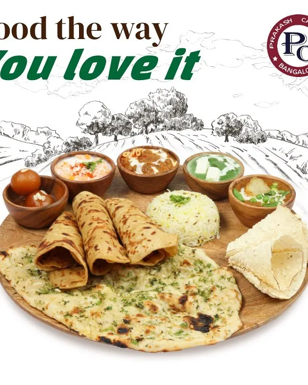 I prepare food the way you love it. This image showcases a classic North Indian thali with an assortment of breads like naan and roti, flavourful curries, rice, and a sweet gulab jamun to finish.