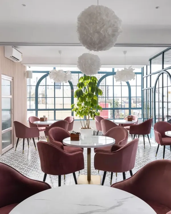 The main seating area of the Zoca rooftop café in Bangalore. The design combines pastel colors, arched windows, and soft, cloud-like light fixtures to create a dreamy, Instagrammable atmosphere.