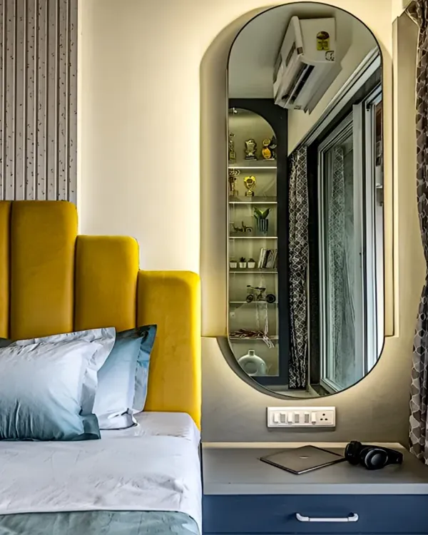 This bedroom features a vibrant yellow upholstered headboard that adds a pop of color. An elegant, full-length mirror with backlighting doubles as a design feature and enhances the room's brightness.