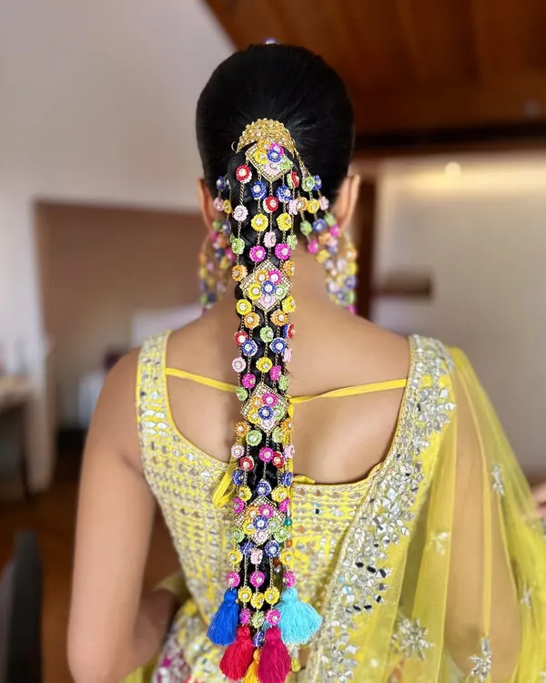 A back view of the spectacular Haldi braid created for Aish. The intricate arrangement of the colorful accessories and tassels creates a waterfall of color that is absolutely breathtaking.