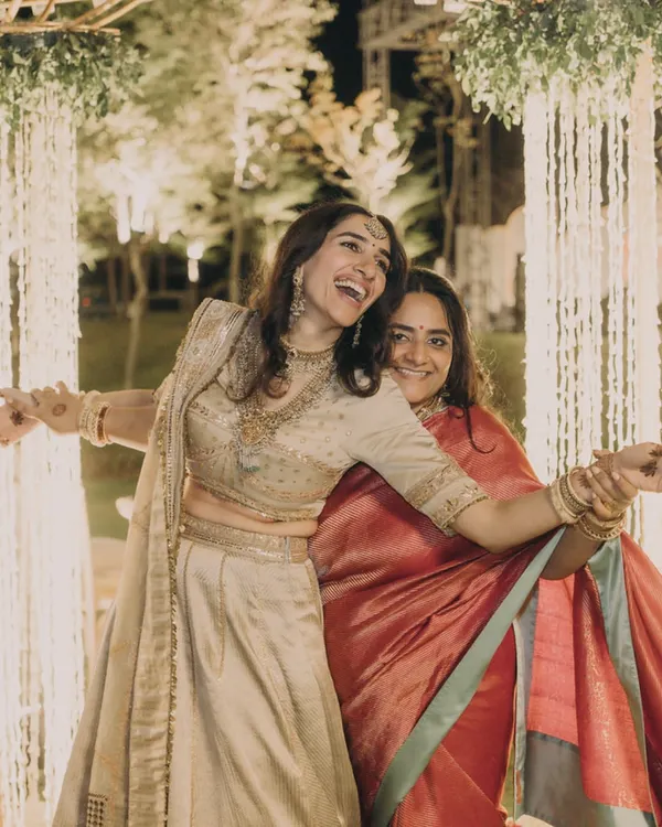 The best moments are the unscripted ones. Here, the bride shares a laugh with her sister-in-law, who we styled in a beautiful red Banarasi saree that complements the bride's lehenga without overpowering it.