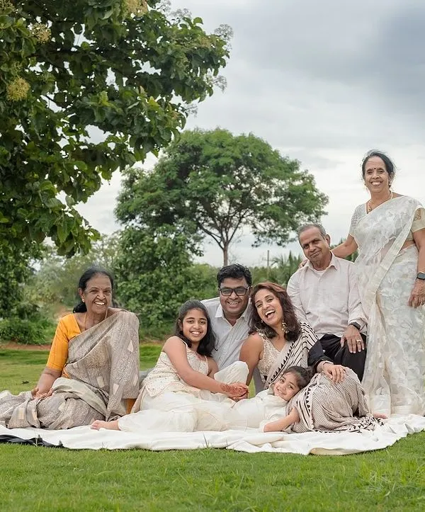 A beautiful portrait of a multi-generational family enjoying a picnic-style shoot outdoors. We find a comfortable spot under a tree where everyone, from grandparents to grandchildren, can relax and be together.