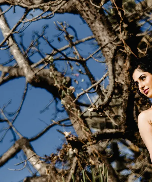 A quiet, contemplative portrait of a bride against a natural backdrop. The low angle and clear blue sky create a simple yet beautiful frame that highlights her elegance.