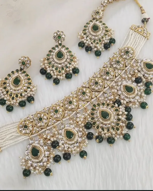 A beautiful Kundan choker set with green stones and pearl drops, complete with matching earrings and a maang tikka.