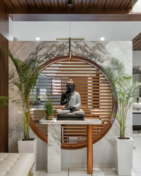 This serene foyer design features a Buddha statue as the focal point, set against a backdrop of marble and wood slats. The design creates a peaceful and welcoming entry into the home.
