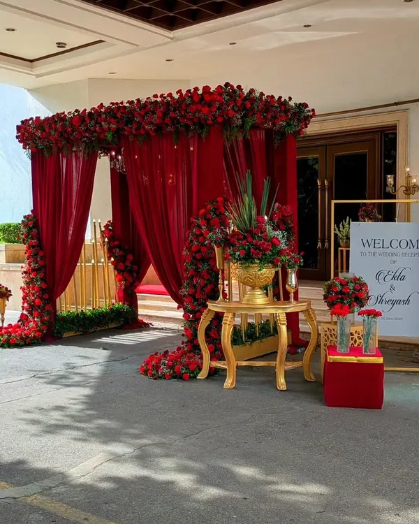For Ekta and Shreyas's reception, I created a regal entrance with a canopy of red roses and sheer drapes, setting a tone of classic romance from the very first step.