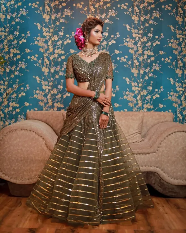 A stunning olive green striped sequin lehenga saree. This modern, pre-draped outfit is perfect for a wedding guest who wants an elegant, hassle-free, and glamorous look.