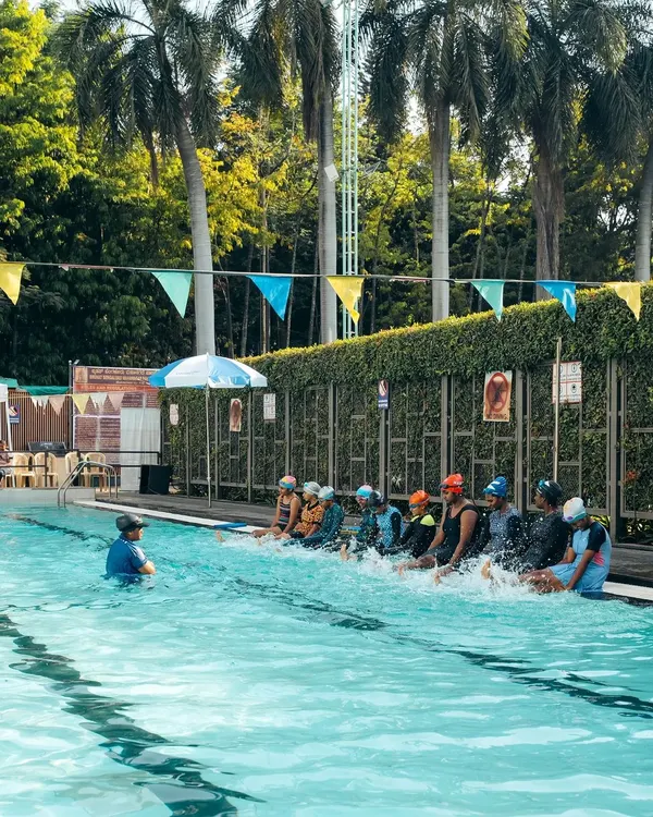 A group of young swimmers learning kicking techniques by the poolside. We use these drills to build leg strength and coordination.