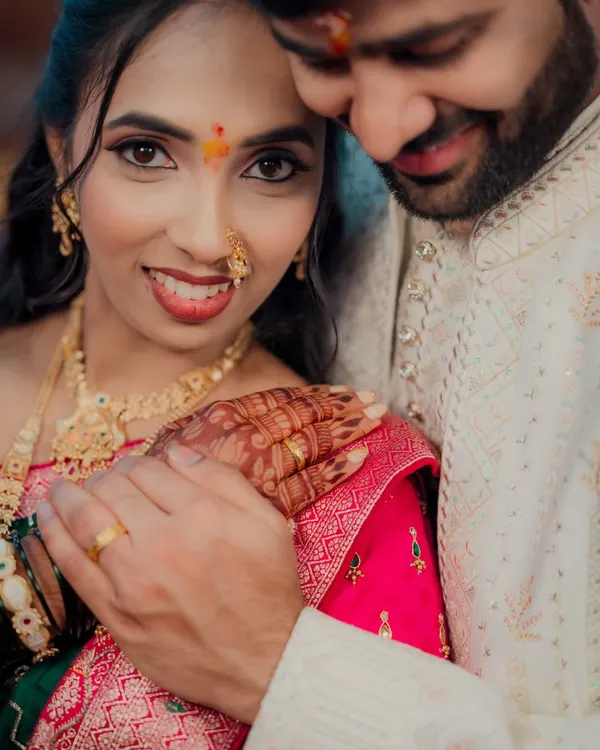 An intimate close-up of a beautiful Maharashtrian bride on her engagement day. Her expressive eyes, traditional nath, and the gentle touch of her partner create a powerful portrait.