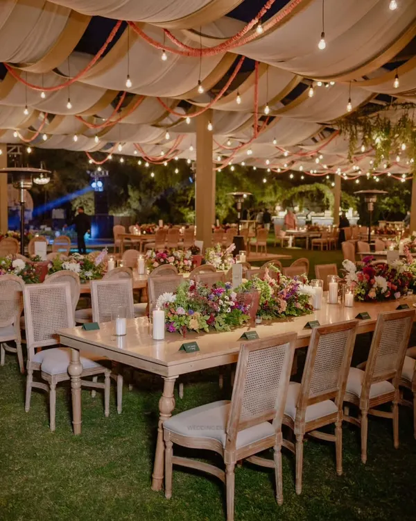 An evening to remember forever. This tablescape features lush floral runners, glowing candles, and elegant place cards, creating a romantic and intimate atmosphere for a reception dinner.