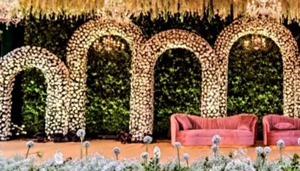 We specialize in creating breathtaking floral installations that serve as the perfect backdrop for any milestone event. This stage features multiple arches constructed entirely from fresh white flowers, creating a truly grand and memorable setting.