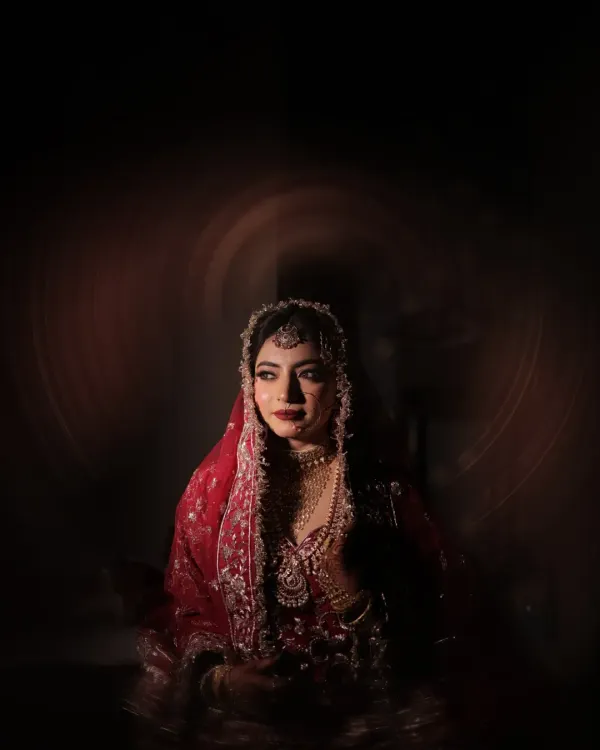 A moment of quiet contemplation. I used dramatic lighting to create this artistic bridal portrait, highlighting her stunning features and the richness of her red lehenga.