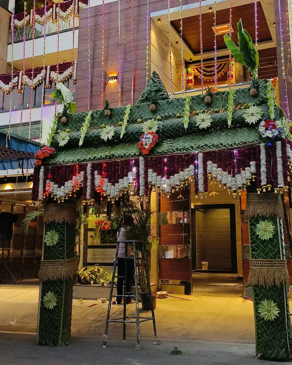 I create these impressive Gruhapravesha entrance arches to welcome guests to your new home. This design features intricate coconut leaf weaving, banana trunk pillars, and flower details for an authentic and auspicious start.