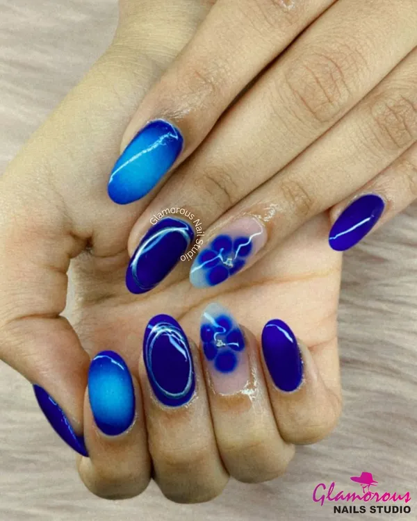 For our clients who love a pop of color, this design is a dream. We used a vibrant royal blue, creating a mix of cat-eye effect, ombré, and solid color nails. The highlight is the accent nails with hand-painted 3D flowers on a clear base, showing our attention to artistic detail.