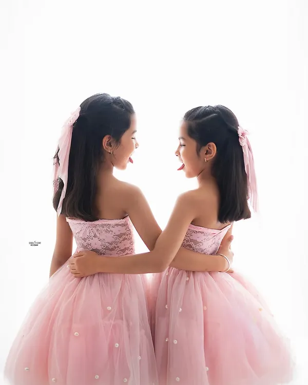 A playful and silly moment between twin sisters. The simple white background makes their fun expressions the star of the show.