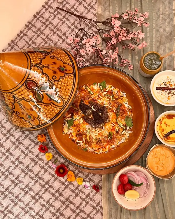 Our Kashmiri Kesar Gucchi Pulao, a rare delicacy served in a traditional pot. This aromatic rice dish features exotic morel mushrooms and is accompanied by saalan, coriander chutney, and our special truffle burani raita for a truly luxurious meal.