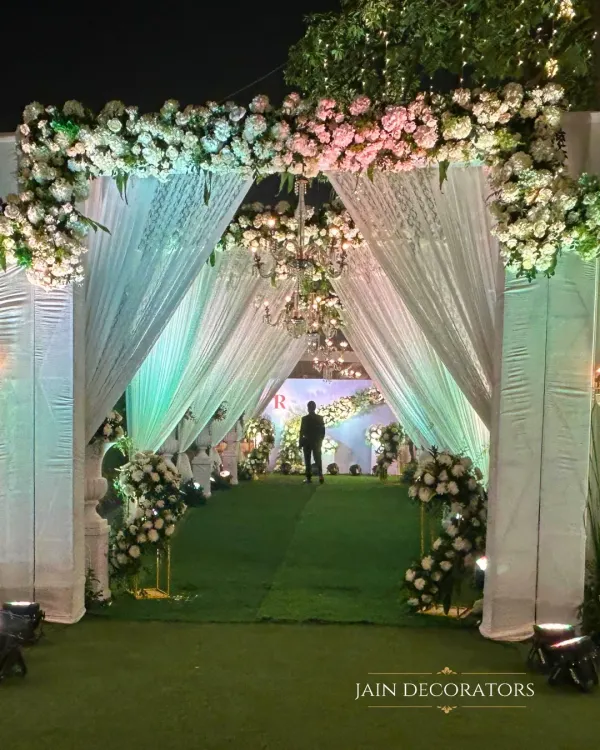 An entrance that whispers elegance. I designed this walkway with flowing white drapes and lush floral arches, leading guests into a serene and magical reception space.