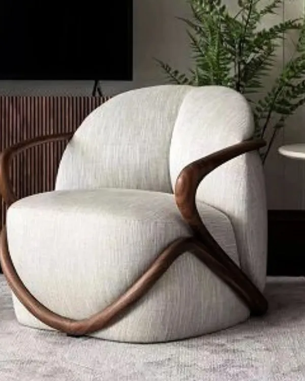 A truly sculptural piece, this accent chair features a unique, flowing teakwood frame that wraps around a plush, upholstered seat. It's a work of art that provides comfortable seating, perfect for making a statement.