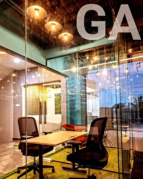 We designed this corporate office in Bangalore with glass partitions and modern pendant lighting to create an open, collaborative atmosphere. The design encourages transparency while defining functional zones like this meeting cabin.