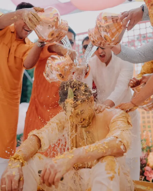 The groom gets a celebratory drenching during a fun-filled Haldi ceremony, a moment of pure, unscripted chaos and joy.