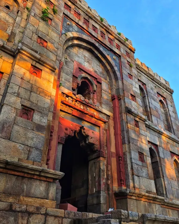 An upward shot of the stunning architecture at Lodi Garden, with the golden hour sun casting a warm glow on the ancient stone. This shows the beauty of Delhi's monuments.