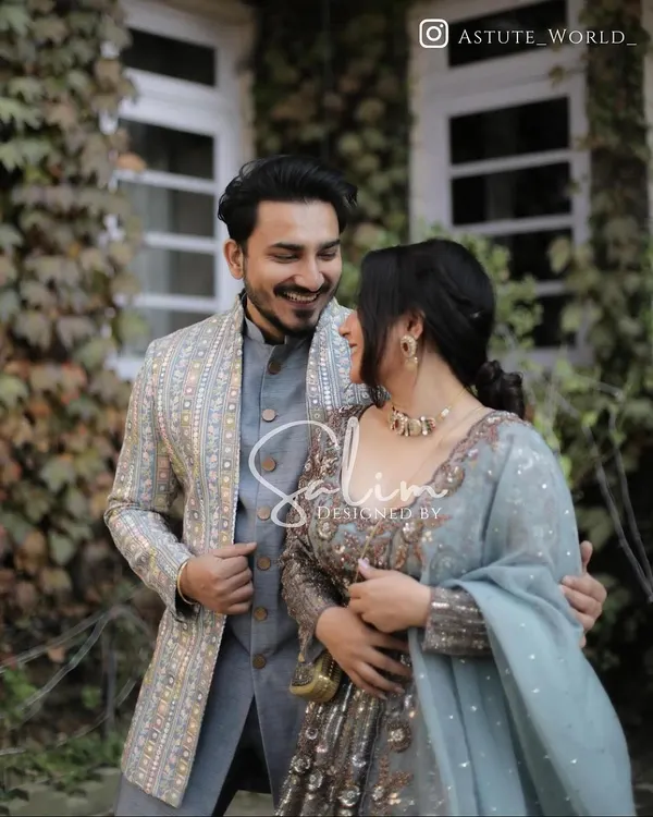 A beautiful shot of a couple enjoying a moment together. I designed the groom's elegant grey-blue Indo-Western outfit, featuring a patterned jacket that complements his partner's attire perfectly.