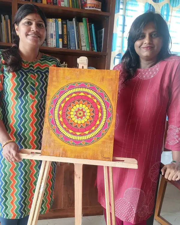 Bhavana with her beautifully completed mandala, painted on a textured background. The warm colors and intricate patterns make this a stunning piece of decor.