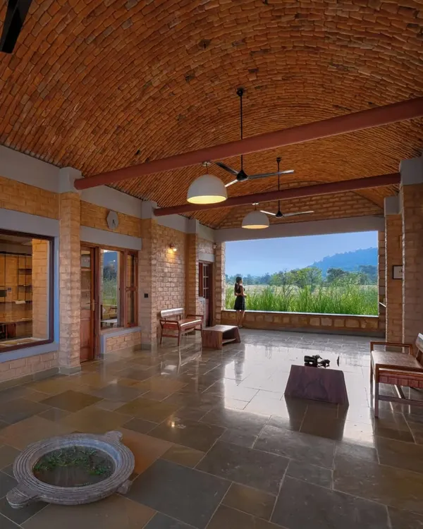The welcome lounge at Waghoba Ecolodge. The space opens up completely to a view of the man-made lake and forest, immediately immersing guests in the natural environment. The vaulted brick ceiling and stone floor keep the area cool.