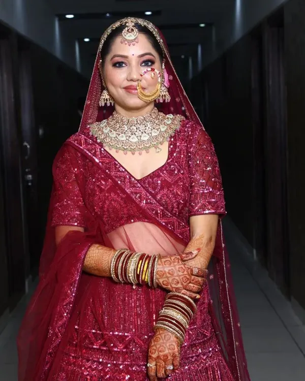 A happy client looking gorgeous in her magenta lehenga and a sparkling Polki choker set for her special event.