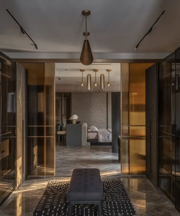 The walk-in closet leading to the master bathroom in the Aikaa villa. We used smoked glass and dark wood to create a moody, luxurious transition, with the bathroom visible beyond.