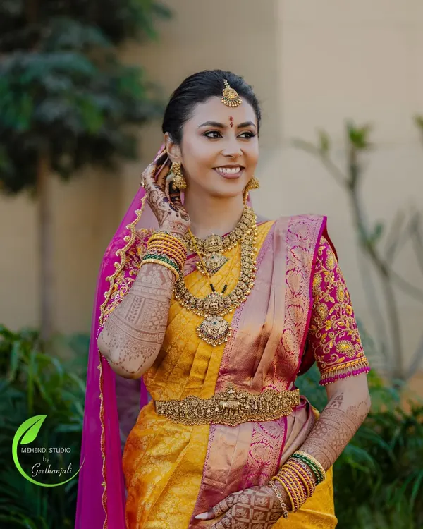 A radiant bride on her wedding day, her beautiful smile complemented by the rich color of her bridal mehendi.