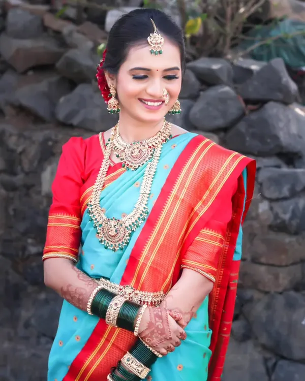 A classic bridal portrait featuring a beautiful bride in a traditional sky-blue and red Paithani saree. The focus is on her serene expression and the rich details of her attire.