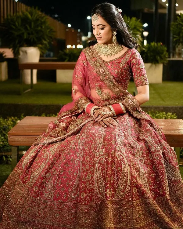 A stunning full-length portrait of the bride in her intricately detailed red lehenga. This shot, taken before the ceremony, captures her elegance and the magnificent craftsmanship of her attire.