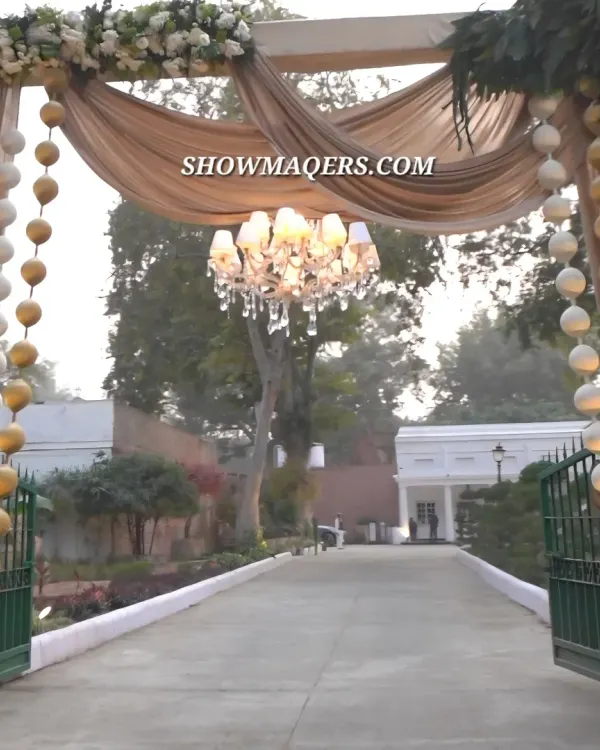 A breathtaking entrance for an ivory and gold themed Roka ceremony. We used draped fabric, floral garlands, and a central chandelier to create a warm and luxurious welcome for guests.