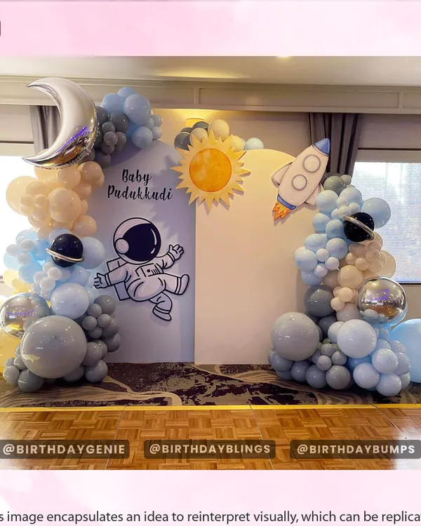 A gentle and dreamy "Baby's First Trip Around the Sun" space theme, using soft pastel blue and cream balloons with moon and rocket accents.